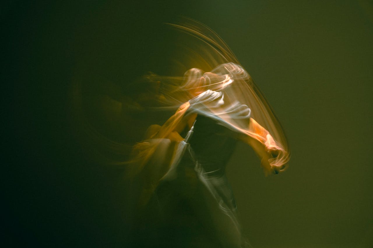 Artistic blurred motion capture of a dancer on stage in deep, warm tones.