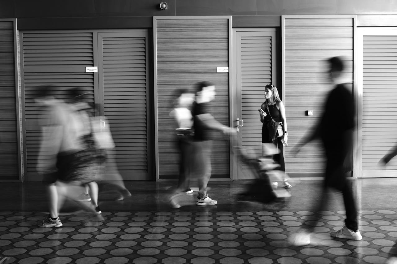 services-01 Artistic black and white image showing blurred motion of people indoors, capturing movement and stillness.
