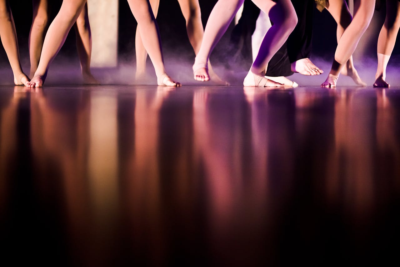 Artistic capture of dancers' feet reflecting on stage floor, creating a dramatic and elegant effect.