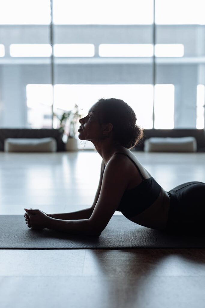 A woman in a yoga position indoors, exuding calm and relaxation on a mat.
