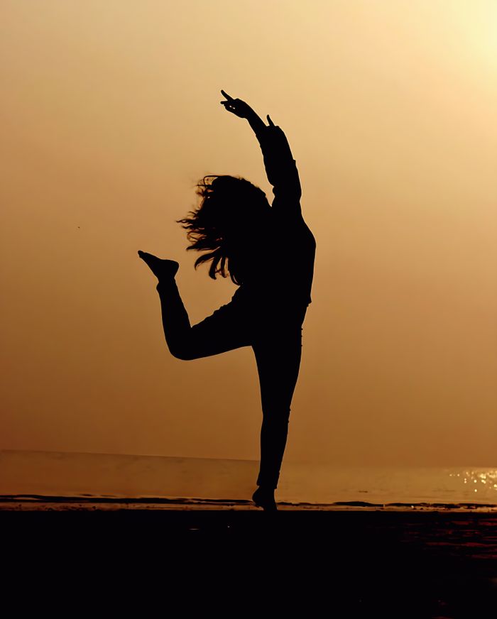 services-04 Silhouette of a dancer expressing joy against a serene sunset beach background.