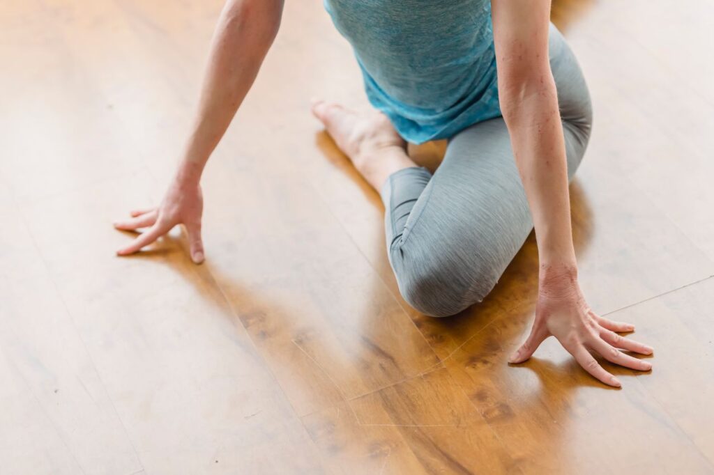 pexels photo 6453946 From above of crop anonymous female performing Eka Pada Rajakapotasana on wooden floor at home in daytime