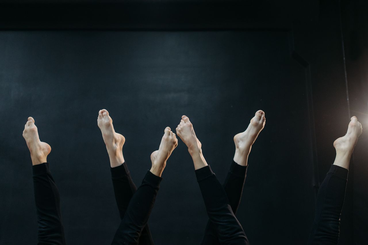 services-img Artistic capture of dancers' legs and bare feet in a minimal studio setting.